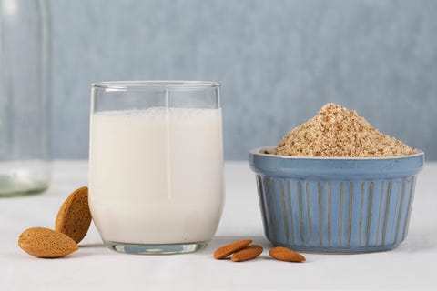 A glass of almond milk with whole and grated almonds