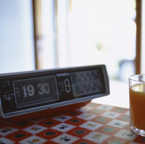 A glass of orange juice next to a clock