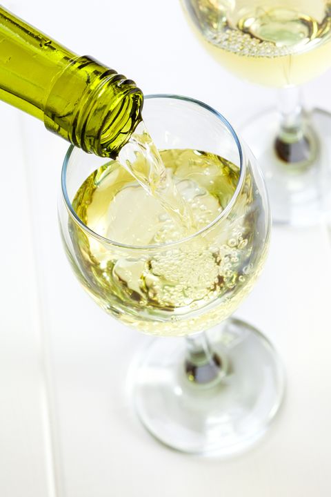 glass of white wine being poured
