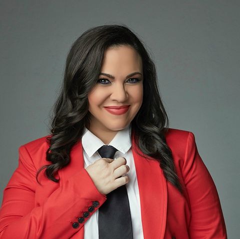gloria calderón kellett is shown wearing a red blazer, white blouse, black pants and black tie
