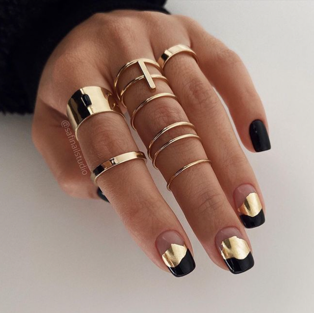 on the left, a hand with black and gold nails and gold rings on a white background, and on the right, a hand with matte black and gold nails on a light brown and white wood background