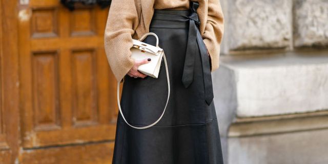 paris, france   march 05 a guest wears a brown wool pullover, a white latte leather kelly handbag from hermes, gold rings, black shiny leather midi skirt, beige  red  blue  black leather and velvet block heels  strappy sandals  shoes, outside hermes , during paris fashion week   womenswear fw 2022 2023, on march 05, 2022 in paris, france photo by edward berthelotgetty images