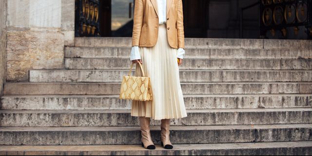 paris, france   march 05 model giedre dukauskaite wears a tan leather blazer, white skirt, a beige pleated skirt, a yellow celine python medium clasp tote, and chanel glitter boots after the stella mccartney show  on march 05, 2018 in paris, france photo by melodie jenggetty images