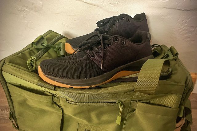 a pair of black gym shoes on top of a duffel bag