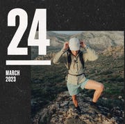 a person on a mountain wearing a hat, jacket, and shorts