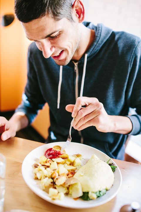 man in gray sweatshirt eating omelette