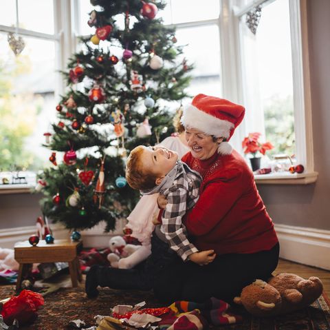 grandmother playing with her grandson in front of the christmas tree