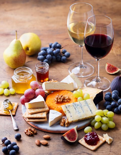 grape, cheese, figs and honey with a glasses of red and white wine on a wooden background