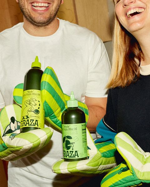 a man and woman standing next to each other and smiling wearing graza mitts holding olive oil