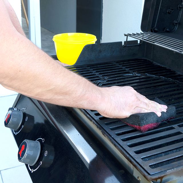 person cleaning grill with sponge