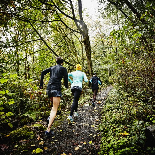 group of female friends running up forest trail