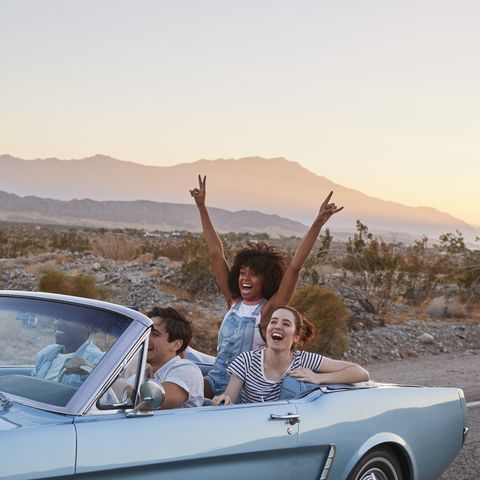 group of friends on road trip driving classic convertible car