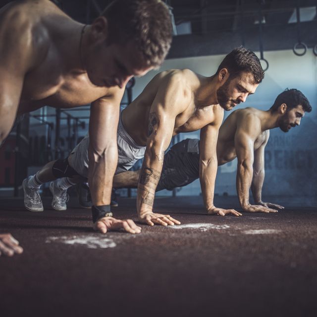 Group of men exercising push-ups in a health club.