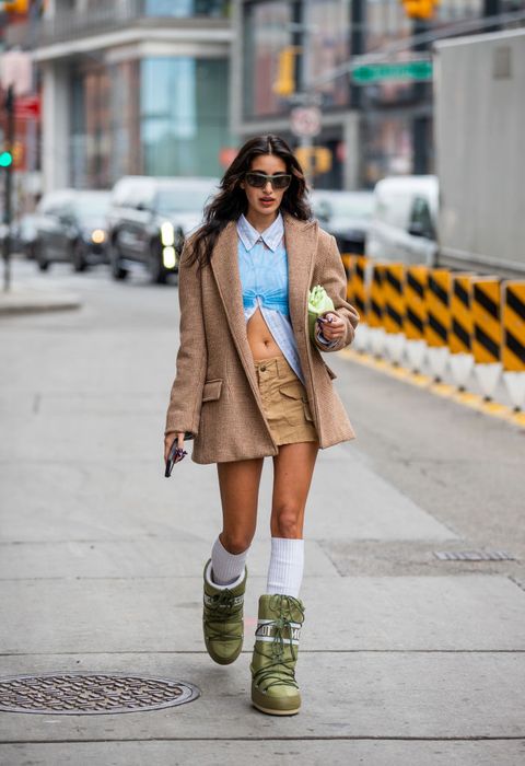vrouw loopt tijdens new york fashion week op straat in beige rok witte sokken en groene moonboots