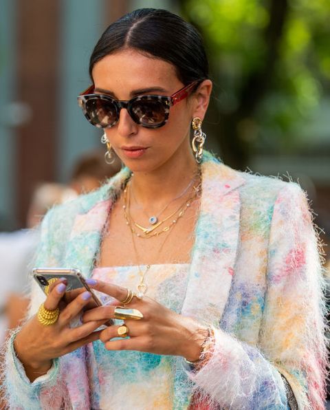 vrouw kijkt op telefoon met oversized zonnebril