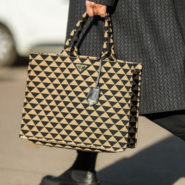 a guest at paris fashion week carries a prada tote bag to illustrate a guide to the best designer tote bags 2023
