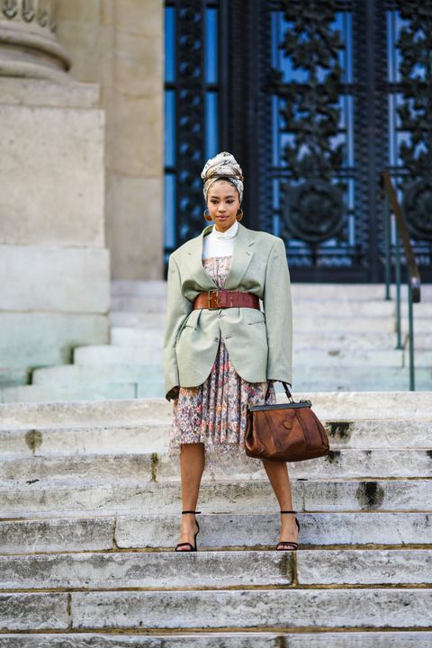 a woman wears a belted blazer over a long skirt in a roundup of the best long skirt outfits 2022