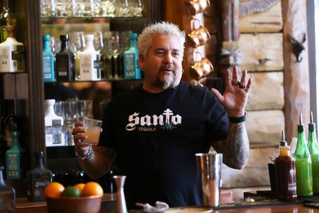 guy fieri holding a tequila drink behind a bar
