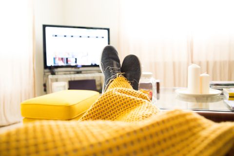 Guy relaxing at home from personal perspective laying in sofa in autumn day covering with blanket while watching television.