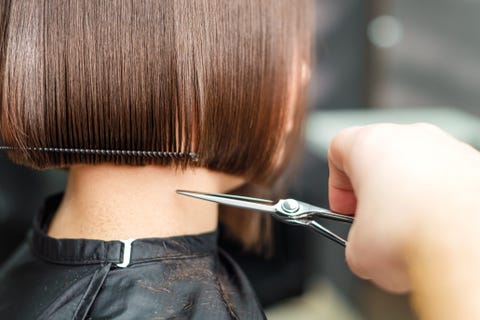 hairdresser's hands are cutting brown short hair