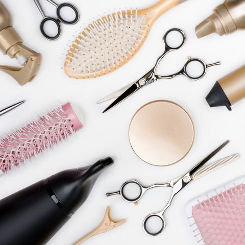 Hairdressing tools and various hairbrushes on white background top view