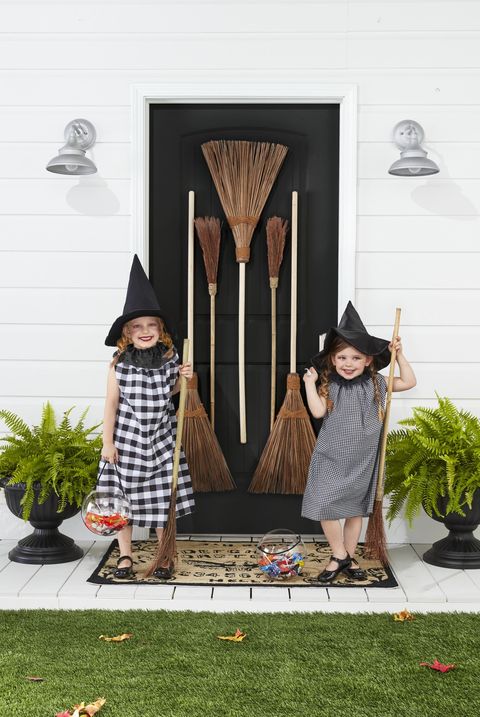 girls wearing halloween witch costumes with brooms