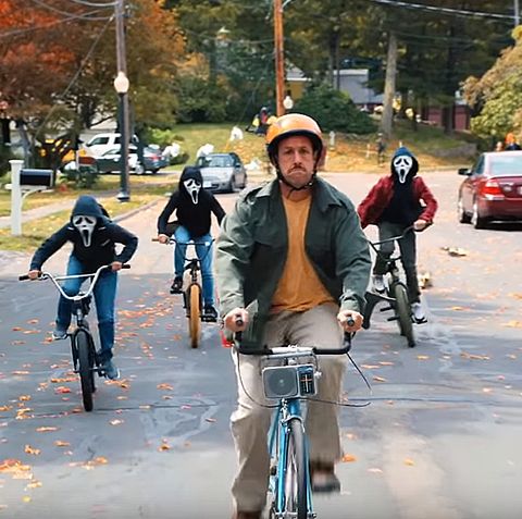 adam sandler's hubie is chased on a bike by kids wearing ghostface masks on their own bikes in a scene from hubie halloween, a good housekeeping pick for best halloween movies on netflix