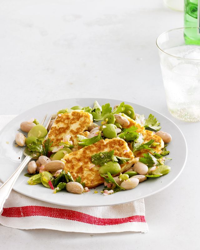 halloumi and shell bean salad on a white plate with a fork and a white napkin with a red stripe