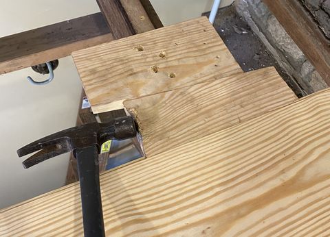 hammering a wedge to close gaps on tongue and groove flooring