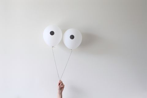 a hand holding a pair of balloons that look like eyes