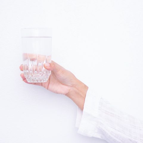 hand holding glass of water against white background
