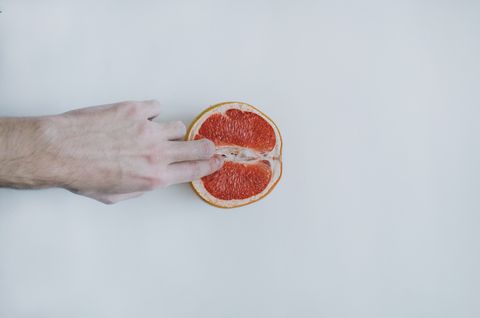 hand holding grapefruit against white background