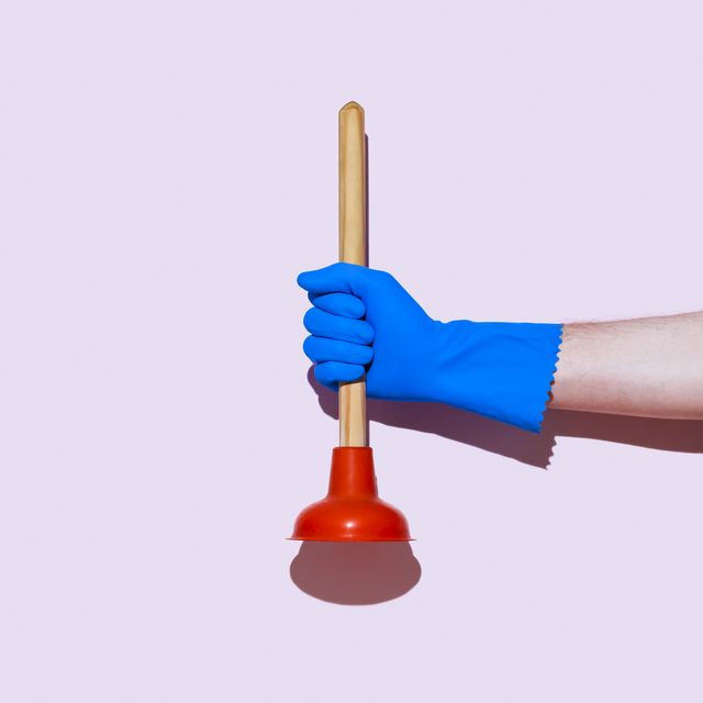 hand in rubber glove holding a plunger