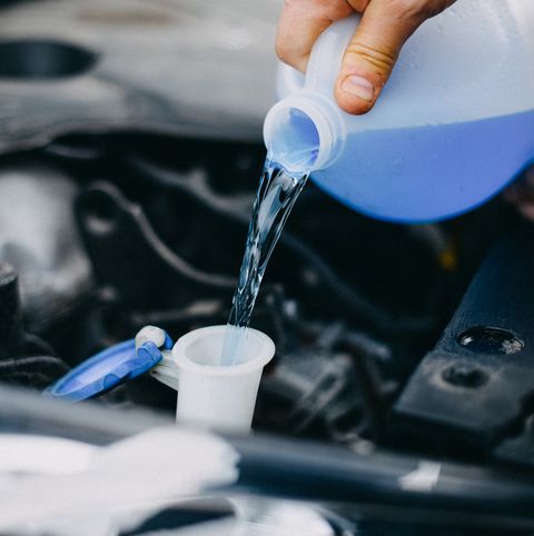 hand pouring windshield washer cleaner in an automobile's tank