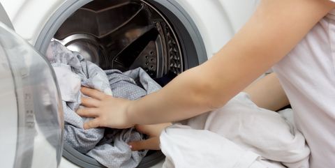 vrouw stopt dekbedovertrek in wasmachine