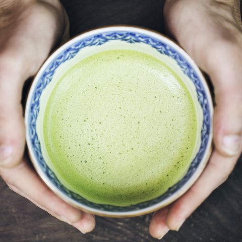 hands of man holding a cup of japanese powdered green tea