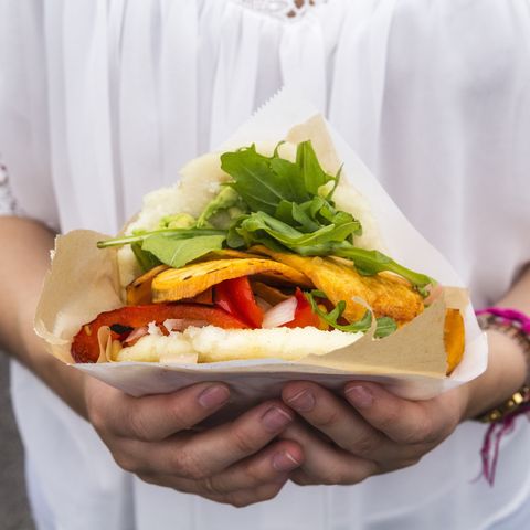 hands of teenage girl holding corn flat bread stuffed with vegetables