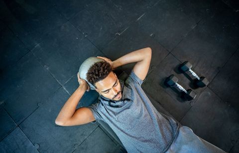 Handsome black man lying on floor working out with a med ball his abs