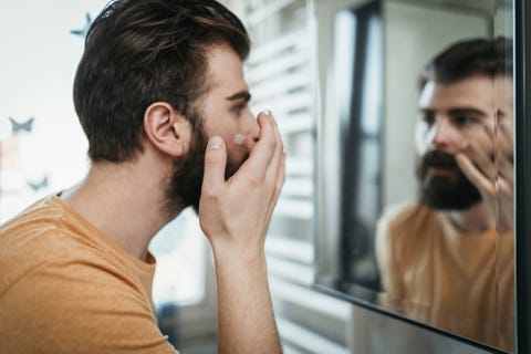 handsome man applying face cream in the bathroom