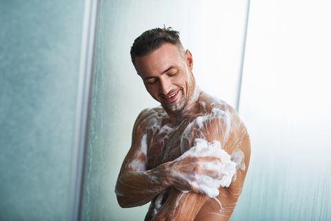 シャワーを浴びながら、身体を洗う男性