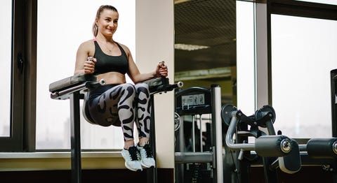 Young fitness woman performing working with abdominal muscles press on the horizontal bar, raises his legs up in gym club. fitness, sport, training concept.