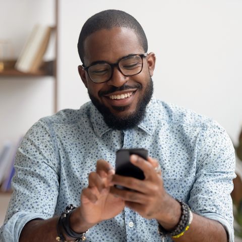 happy african american businessman using phone mobile apps at workplace