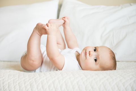 Happy baby boy holds toes