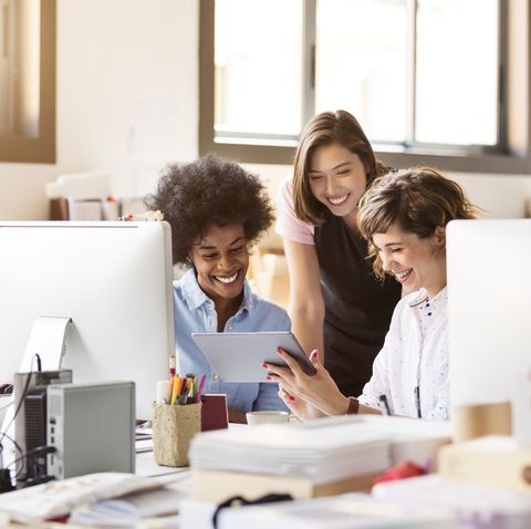 happy businesswomen using digital tablet in office