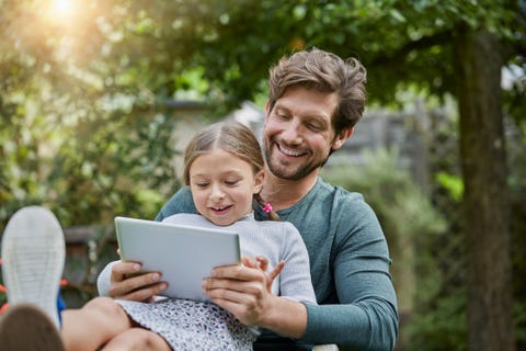 Happy father and daughter using tablet together in garden