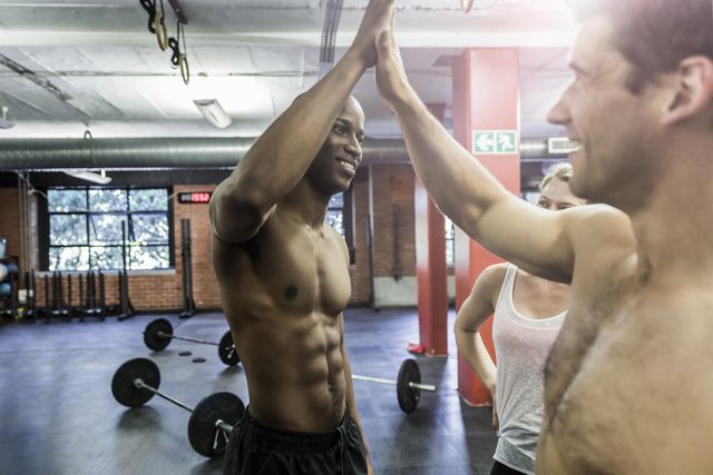 happy male athletes giving high five in gym