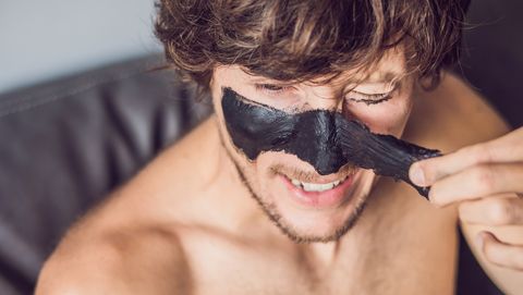 man trekt masker met actieve houtskool van zijn gezicht