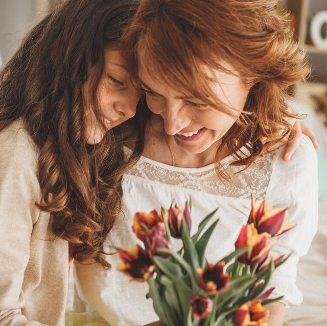 happy mother and daughter hugging and holding a bouquet of fresh flowers