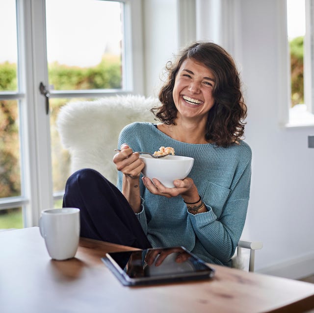 happy woman having breakfast at dining table