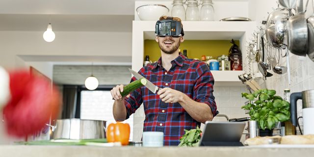 happy young man wearing vr glasses cooking in kitchen